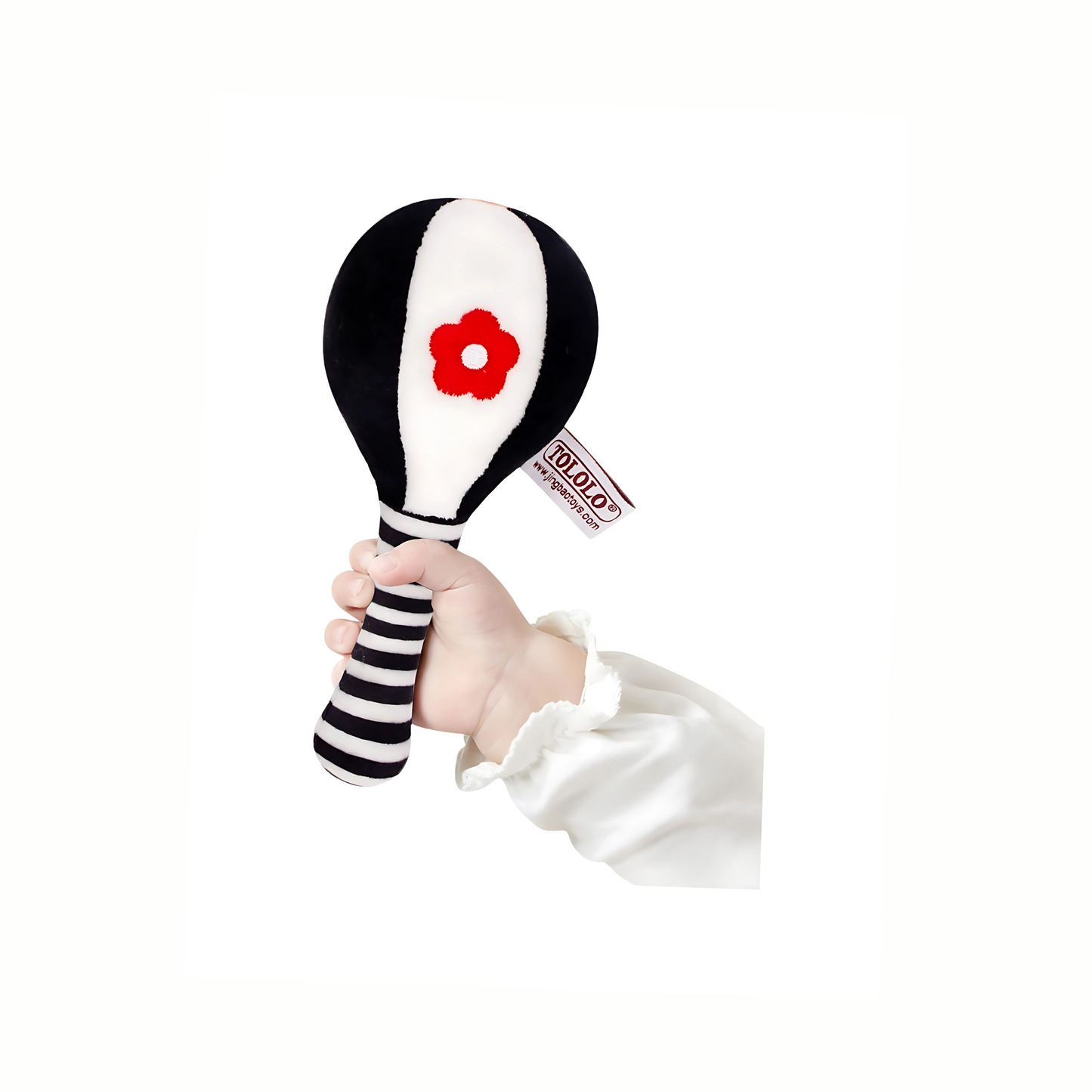 Baby's hand gently holding a plush black and white rattle, showing easy grip for infants