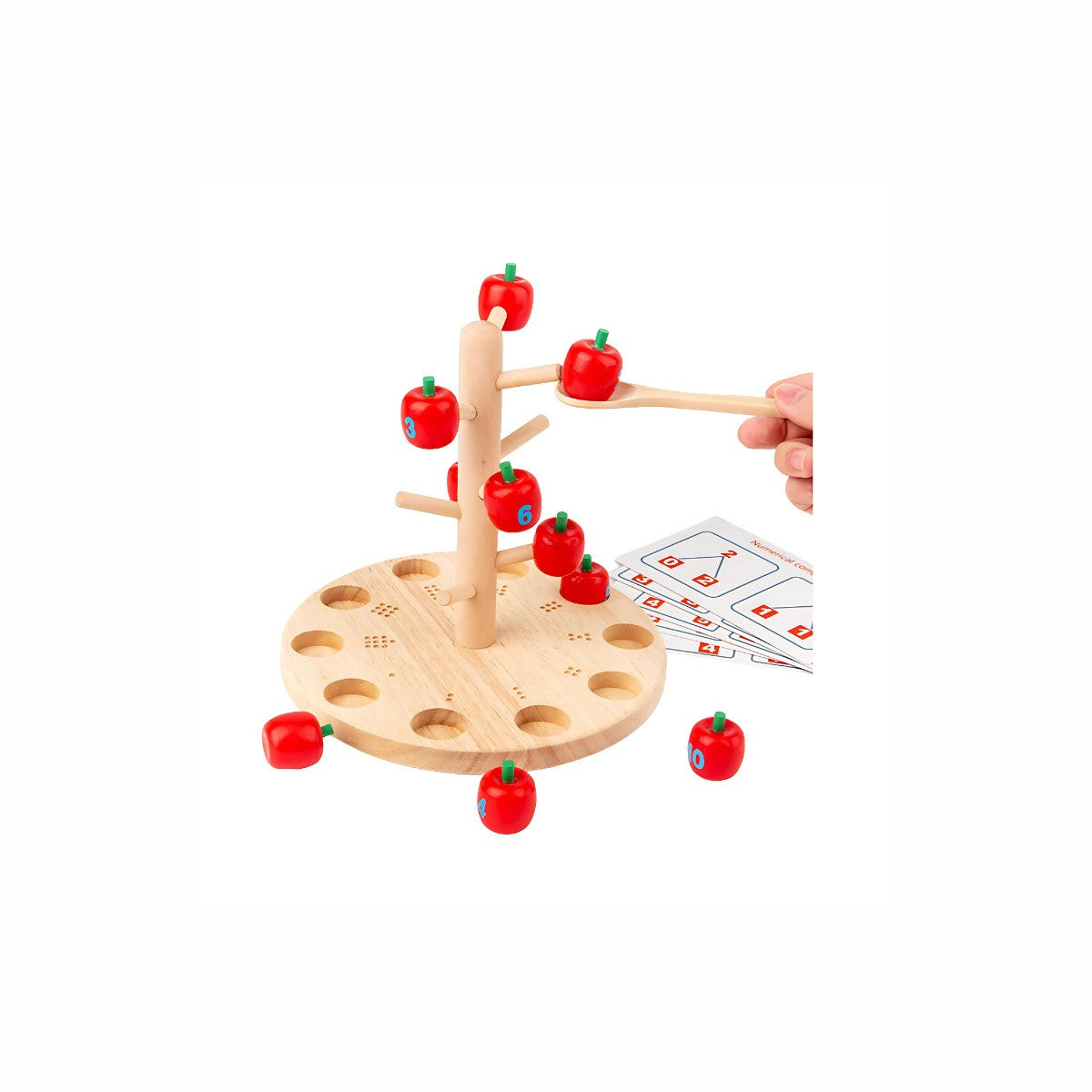 A hand carefully collecting an apple with the wooden spoon from the Wooden Apple Tree Counting Game, practicing fine motor skills and hand-eye coordination.