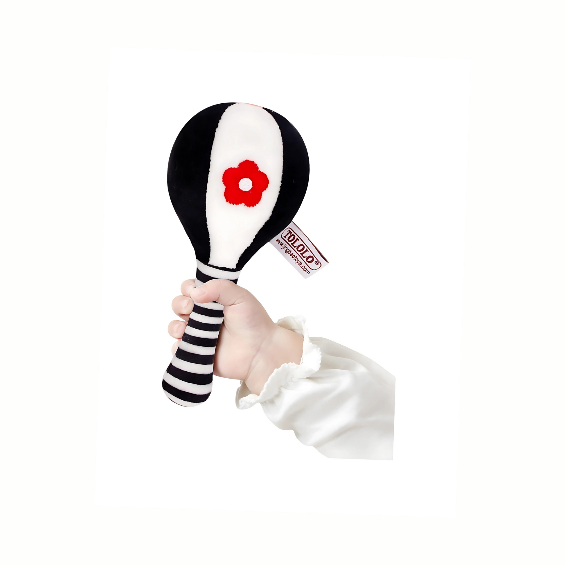 Baby's hand gently holding a plush black and white rattle, showing easy grip for infants