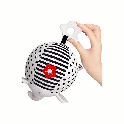 A hand holding the white textured end of the Plush Black & White Sensory Toy, showing the easy grasp for baby and the soft, friendly plush material.