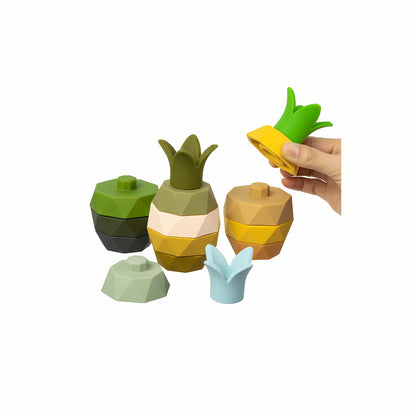 A hand stacking a slice onto the Silicone Pineapple Stacking Toy, demonstrating the easy grasping motion that encourages the development of fine motor skills and hand-eye coordination