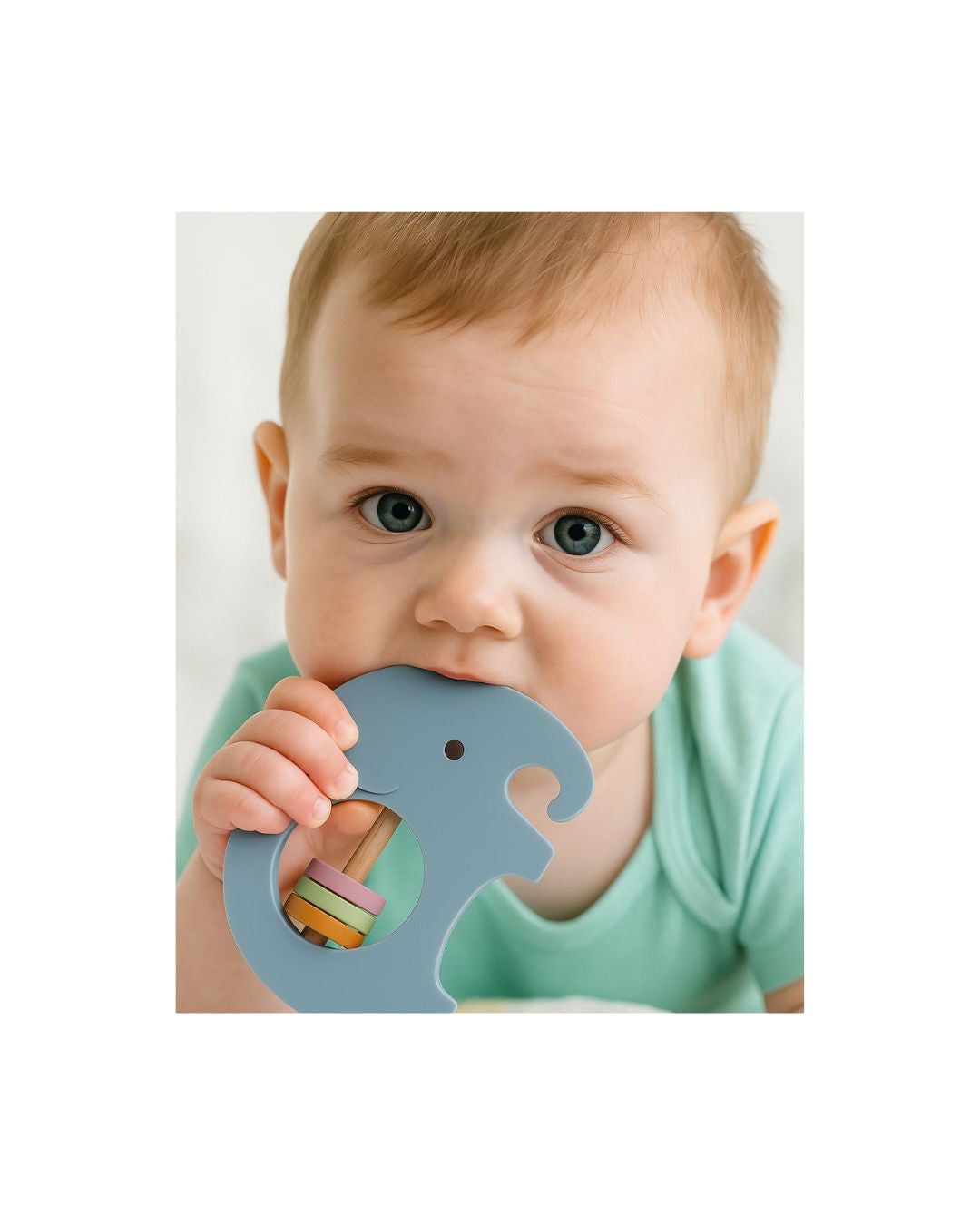 A baby happily biting on the blue elephant Silicone Rattle Teether, demonstrating the textured surface that offers soothing relief during teething.