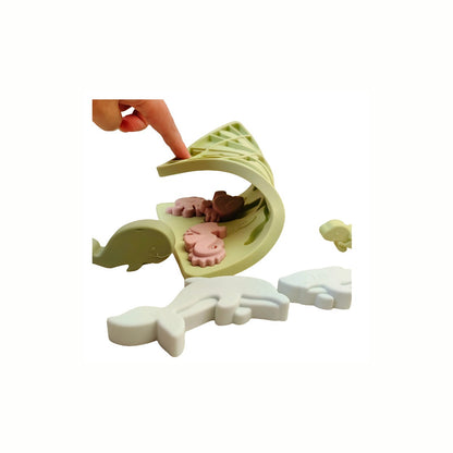 A hand bending a piece of the Silicone Sea Creatures Puzzle, demonstrating the soft, flexible texture which is safe and tactile for fine motor skills.