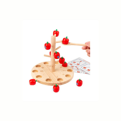 A  hand carefully collecting an apple with the wooden spoon from the Wooden Apple Tree Counting Game, practicing fine motor skills and hand-eye coordination.