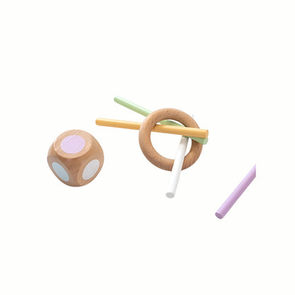 A close-up of the Wooden Balance and Posting Sticks Game set, showing the colorful sticks stacked in the wooden ring and the color die used for turn-taking play.