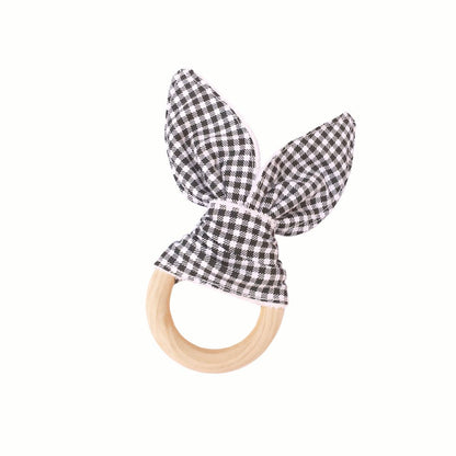Full view of the black and white gingham Wooden Bunny Teething Ring, a simple, effective way to provide relief and a touch of natural charm to the baby's teething journey.