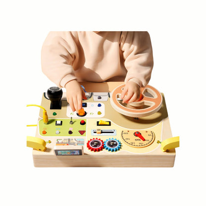 A child playing with the Wooden Interactive Busy Board (Steering Wheel variant), actively turning the horn and key for imaginative role-play.